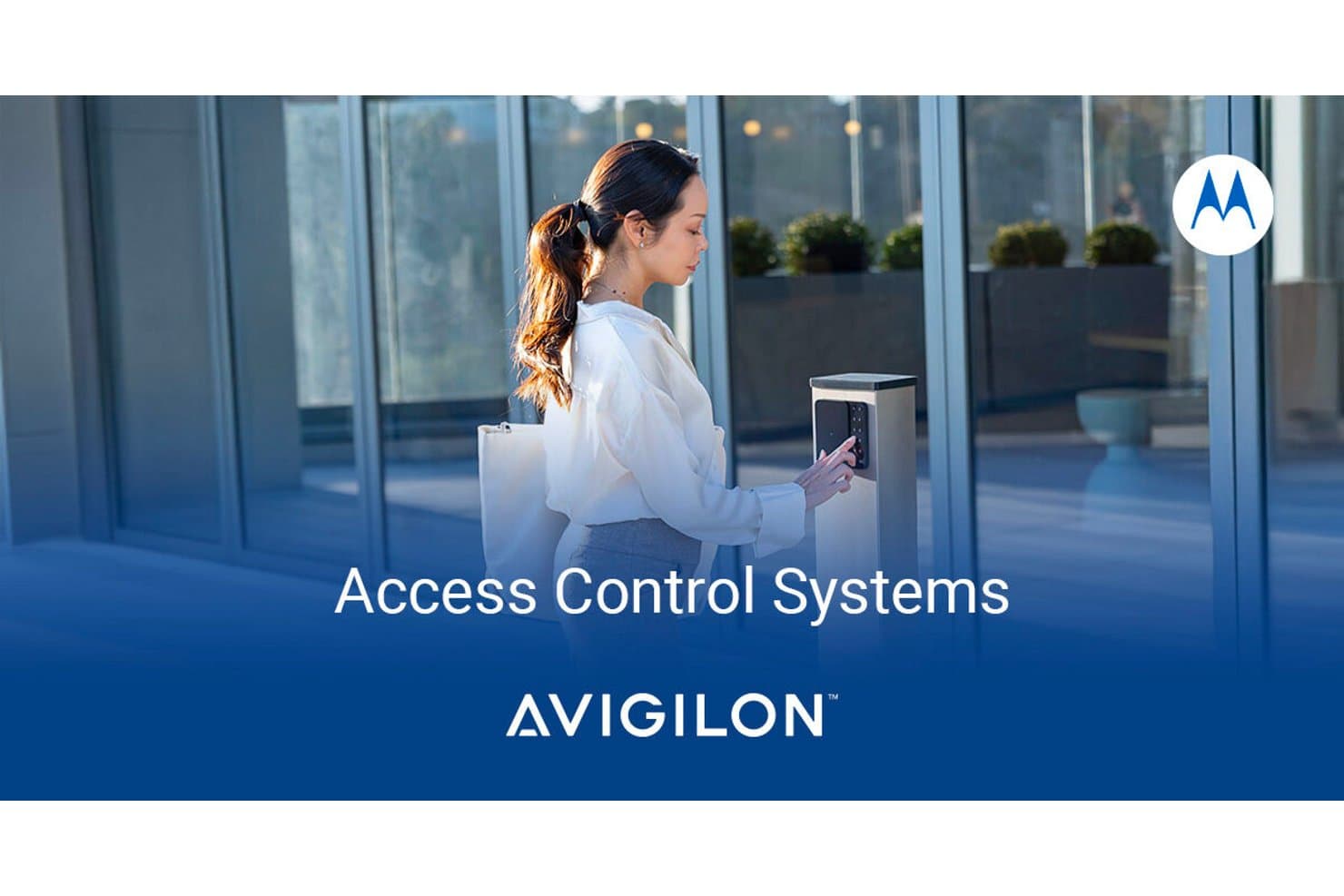 Woman using a keypad access control terminal outside a glass building entrance.