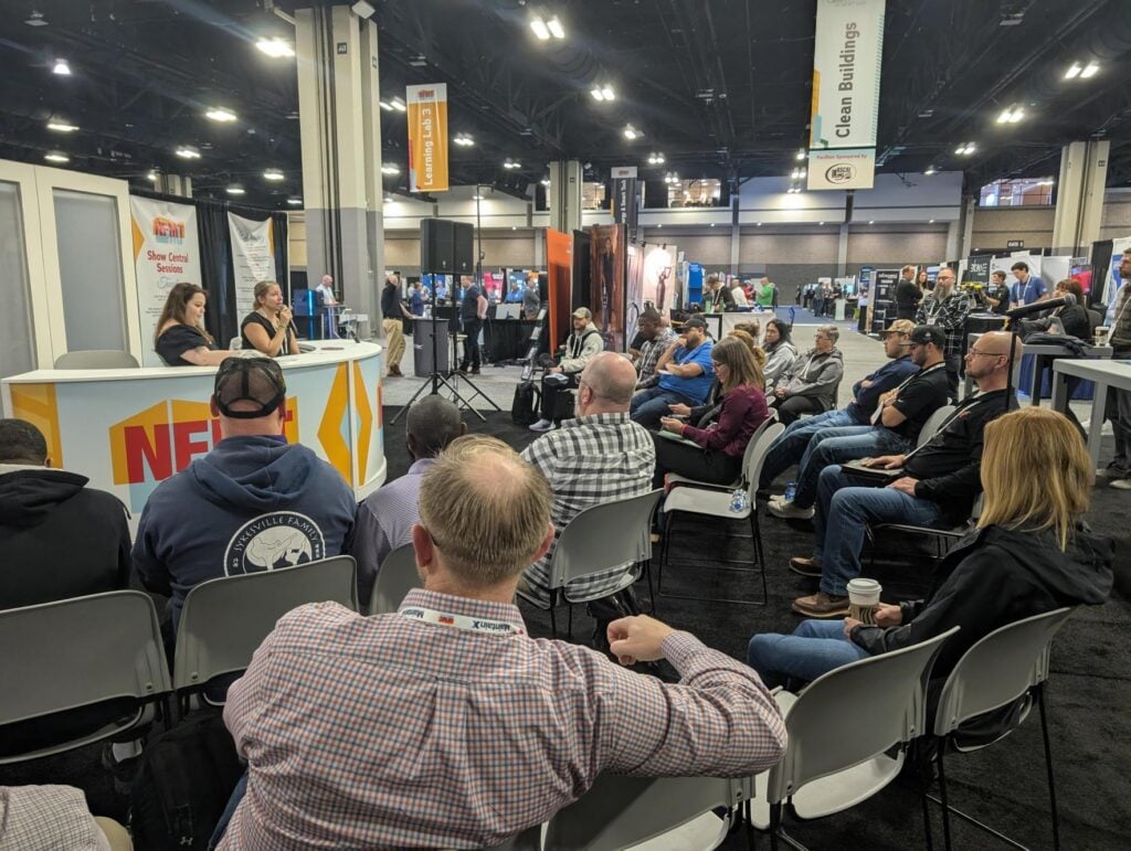 Audience seated around a presentation area during a live session at the National Facilities Management &amp; Technology Conference &amp; Expo