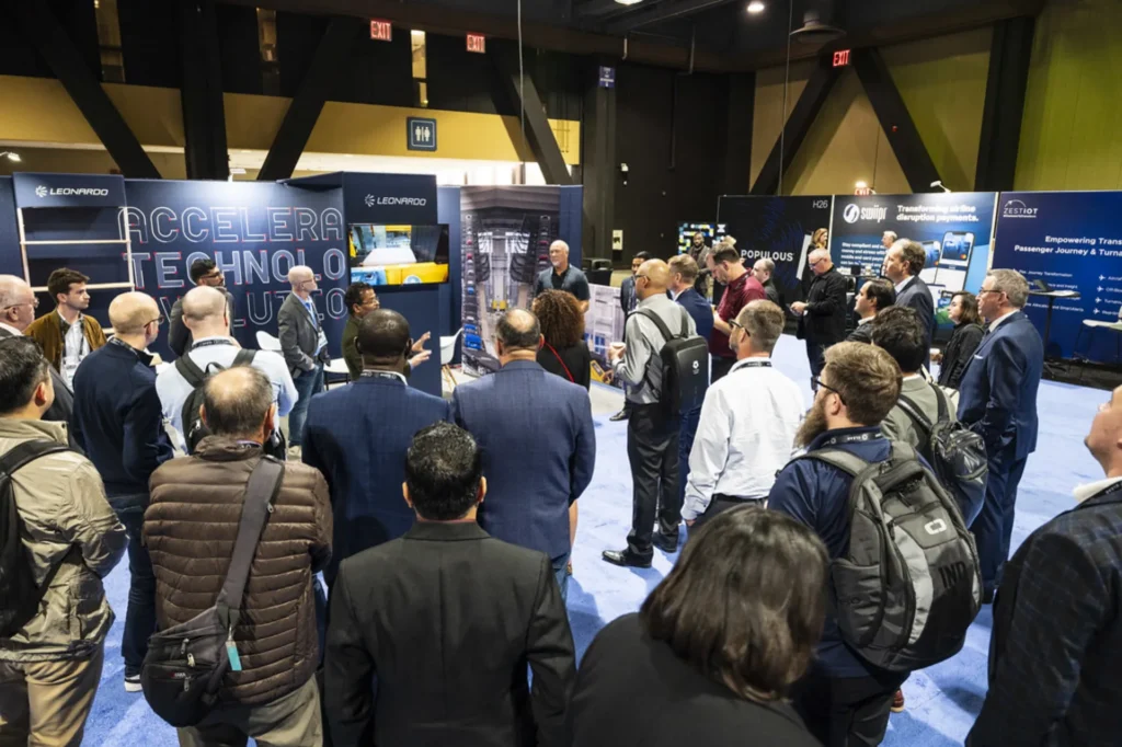 Attendees gather around an exhibitor booth during Future Travel Experience Global, watching a technology demonstration on the show floor
